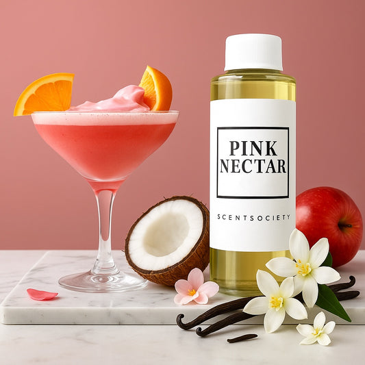 Scent Society PINK NECTAR premium diffuser fragrance oil in a clear 100ml plastic bottle with white label and cap, displayed on a marble surface with an apple, half a coconut, vanilla pods, white flowers and pink flower petals, and a pink cocktail garnished with an orange slice set against a soft pink background.