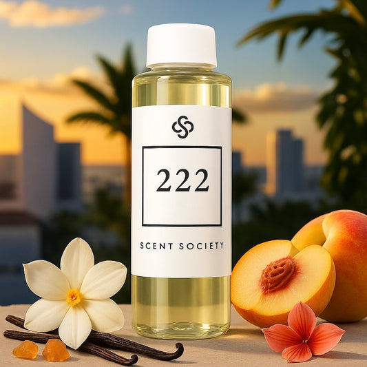 Scent Society 222 premium diffuser fragrance oil in a clear 100ml plastic bottle with white level and cap, displayed on a beige surface next to a halved peach, vanilla flower and vanilla pods, amber and red flower, with a sunset city skyline and palm trees in the background.