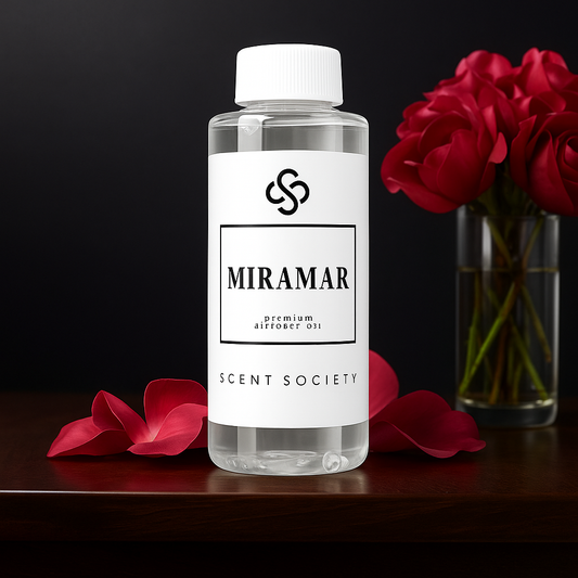 Scent Society MIRAMAR premium diffuser fragrance oil in a clear 100ml plastic bottle with white label and cap, placed on a dark surface with scattered red rose petals and a bouquet of red roses in the background.