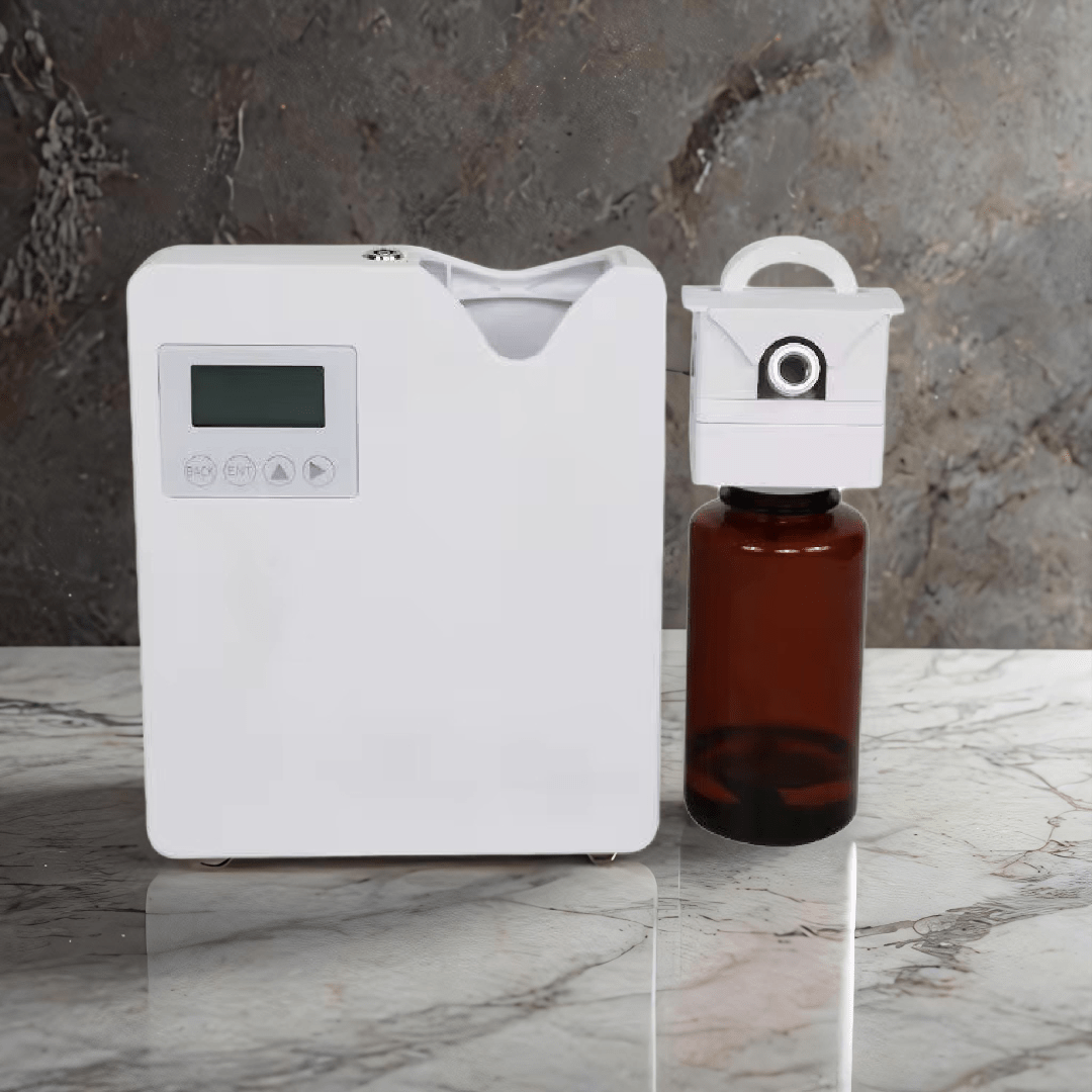 Scent Society Founder white commercial-grade diffuser machine with digital LCD display and detachable scent cartridge, shown next to a large amber fragrance oil bottle on a marble surface with a stone background.