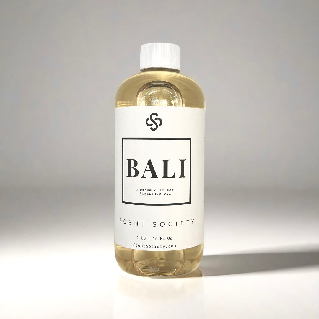 500ml bottle of Scent Society labeled 'BALI' diffuser oil on a neutral background. Clear plastic bottle with white cap and minimalist black-and-white label, filled with fragrance oil. Aromatherapy oil for use in cold air diffusers.