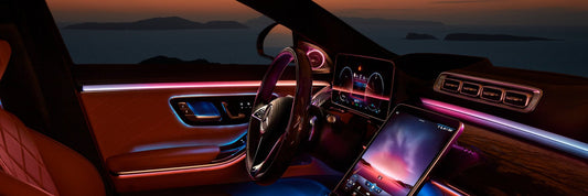 A luxury car interior at dusk illuminated inside with red and blue light panels.