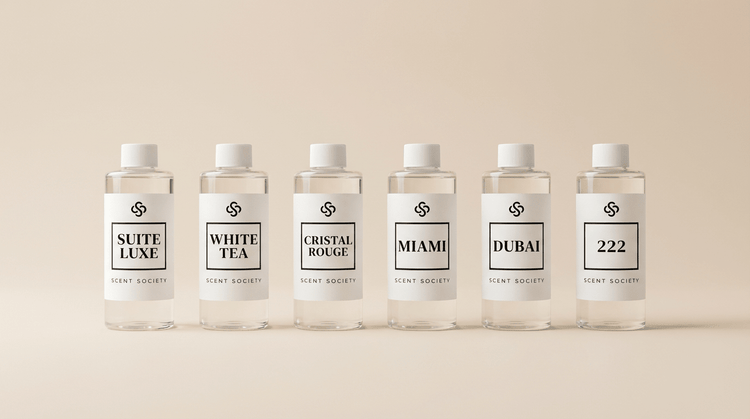 Six Scent Society diffuser oil bottles in the scents Suite Luxe, White Tea, Cristal Rouge, Miami, Dubai, 222 on a neutral background.