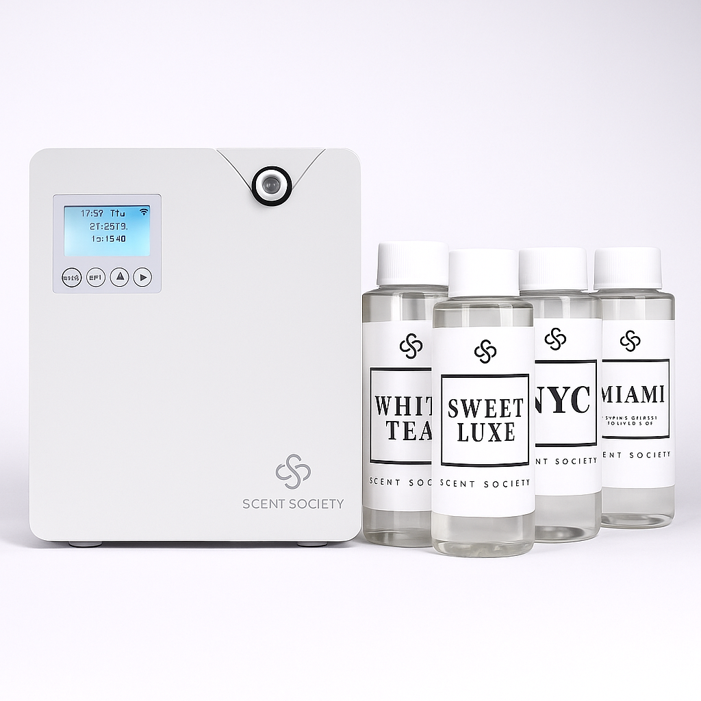 White square diffuser machine with Scent Society logo on bottom right corner. Four 100ml bottles of diffuser oils with white labels and white caps with fragrance names White Tea, Sweet Luxe, NYC, Miami