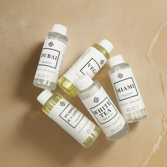 Five small bottles with labels on a beige background. Scent Society Fragrance Diffuser Oils in Dubai, Vegas, pumpkin & Vanilla, White Tea, Miami