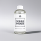 Clear bottle of 'Sugar Cookie' diffuser oil by Scent Society on a gray background