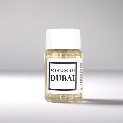 20ml bottle of Scent Society labeled 'DUBAI' diffuser oil on a neutral background. Clear plastic bottle with white cap and minimalist black-and-white label, filled with fragrance oil. Aromatherapy oil for use in cold air diffusers.