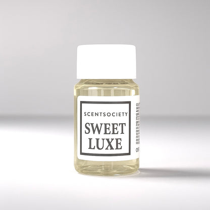 20ml bottle of Scent Society labeled 'SWEET LUXE' diffuser oil on a neutral background. Clear plastic bottle with white cap and minimalist black-and-white label, filled with fragrance oil. Aromatherapy oil for use in cold air diffusers.
