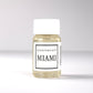 20ml bottle of Scent Society labeled 'MIAMI' diffuser oil on a neutral background. Clear plastic bottle with white cap and minimalist black-and-white label, filled with fragrance oil. Aromatherapy oil for use in cold air diffusers.