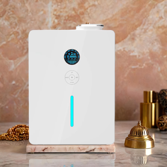 White rectangular scent diffuser with digital LED display, control panel, and vertical teal light, displayed on a marble surface with gold hotel bell and accessories - luxury fragrance diffuser for large spaces or hospitality settings.