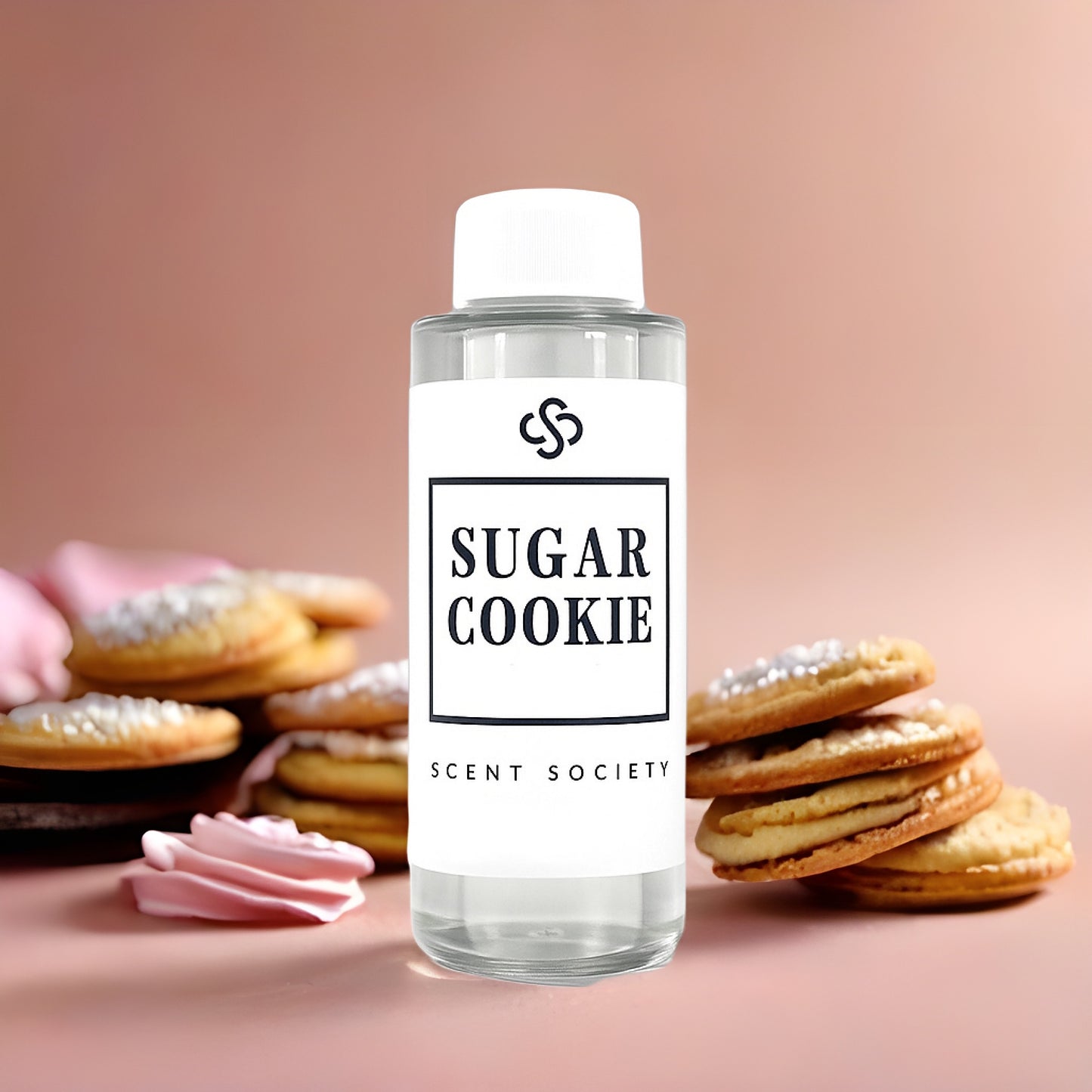 Clear bottle of 'Sugar Cookie' diffuser oil by Scent Society with cookies and pink cream on a pink background