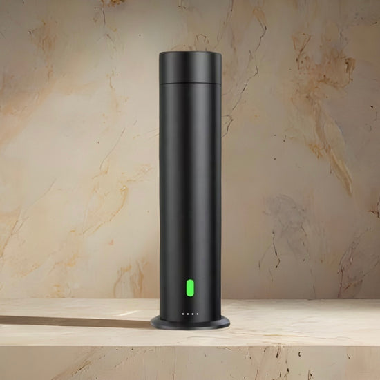 Black cylindrical device with a green light on a marble surface