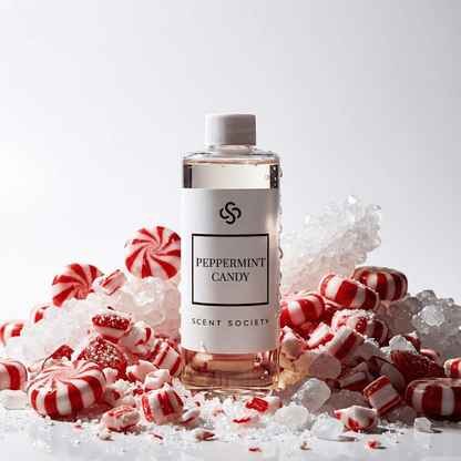 Scent Society Peppermint Candy diffuser oil bottle displayed upright on a white surface, surrounded by crushed peppermint candies and sugar crystals, photographed on a clean white background