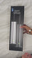A woman’s hand opens a white box revealing a tower diffuser, user manual, remote control, power cord, and accessories neatly arranged inside. She lifts the diffuser to open it, displaying the internal bottle pre-filled with fragrance oil. She holds up the remote control, then shows the diffuser plugged in with a glowing green LED light indicating the machine is powered on and in use.
