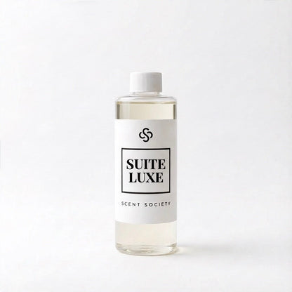 Scent Society's Suite Luxe clear diffuser oil bottle with white cap and white label on a white background