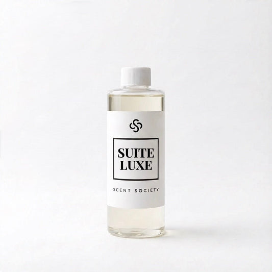 Scent Society's Suite Luxe clear diffuser oil bottle with white cap and white label on a white background